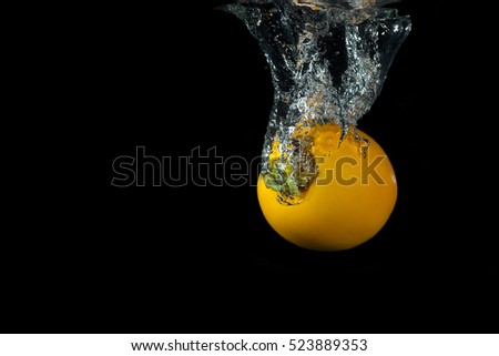Fresh kaki in water with air bubbles water splash isolated on black