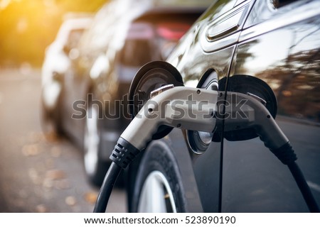 Electric car charging on parking lot with electric car charging station on city street. Electric cars in the row ready for charge. Close up of power supply plugged into an electric car being charged.
 Royalty-Free Stock Photo #523890190