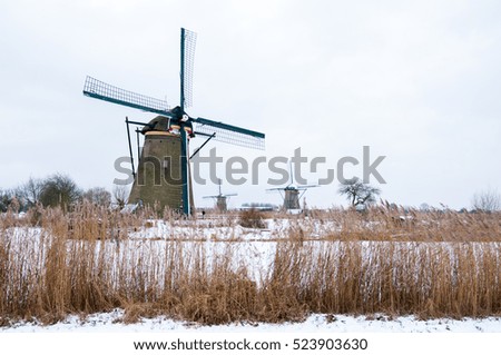 Windmill in a winter landscape with snow and ice at Kinderdijk Holland Royalty-Free Stock Photo #523903630