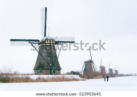 Windmill in a winter landscape with snow and ice at Kinderdijk Holland Royalty-Free Stock Photo #523903645
