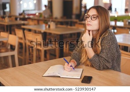 Business woman writing to do list in a cafe Royalty-Free Stock Photo #523930147