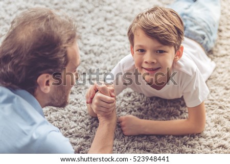 Father and son are wrestling and smiling while spending time together at home