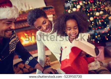 
Happy smiling African American family in Christmas atmosphere opening Christmas present