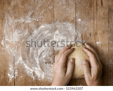 fresh raw dough and bakers hands on rustic wooden table, top view
