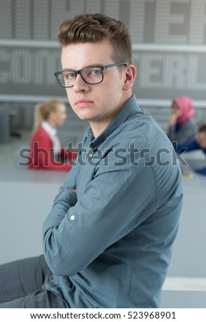 Portrait of happy young businessman  in office, people working in background.