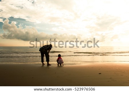 Happy family cute little boy ans dad play on beach sunrise background