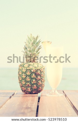 Pina colada cocktail with pine apple at the sea pier. Concept of luxury vacation. Beach party. Upscale resort background. Blue sky at the background. Vertical