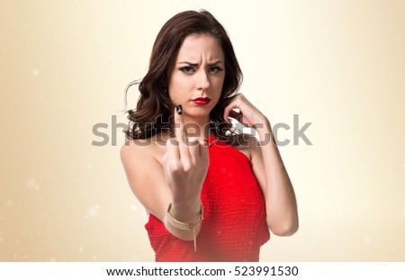 Pretty young girl making horn gesture on ocher background