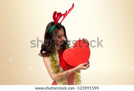 Pretty young woman with christmas items and reindeer antlers on ocher background