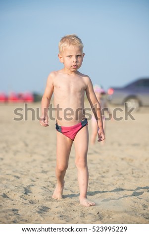 Baby boy walking on the sandy beach near the sea. Cute little kid at sand tropical beach. Ocean coast.