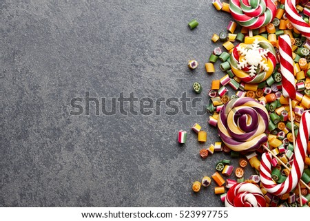 Colorful lollipops, candy canes and sweet candies mix on stone textured background