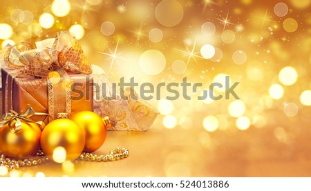 Christmas and New Year Gold color Gift Box and decorations, baubles and tinsel border art design. Winter Holiday celebration art design. Golden Christmas blurred abstract Background 
