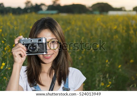 beautiful Asian young girl taking a photo at the flower field by film vintage camera