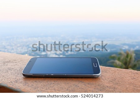 Mobile Phone on wood, City and mountain Background.