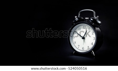 black retro alarm clock in dark background.For time concept.