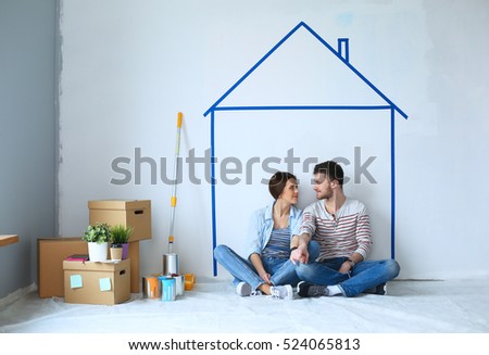 Couple sitting in front of painted home on wall Royalty-Free Stock Photo #524065813