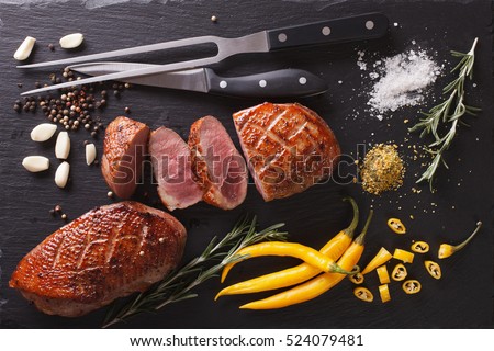 Roast duck fillet with herbs and spices closeup on a slate board. Horizontal view from above
