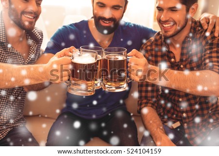 Three happy men clinking with glasses of beer on christmas