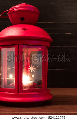 Red christmas lantern on natural brown wooden table. Copy space to the right. Black background. Vertical orientation.