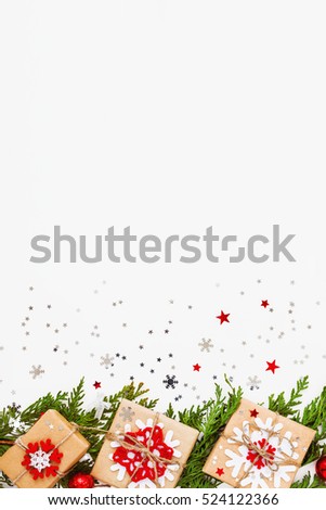 Christmas and New Year background with thuja branch, decorations and presents wrapped in craft paper with snowflakes. Flat lay, top view. Place for text.