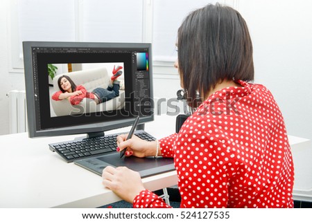 Young brunette female designer using graphics tablet while working with computer