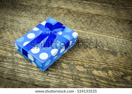 Blue little present in peas on wooden background 