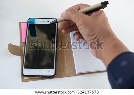 Mobile phone notebook and pen on white background
