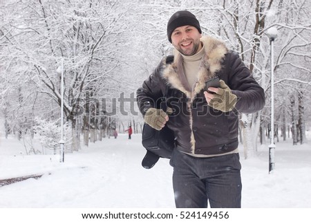 bearded man walking in a winter park snow season