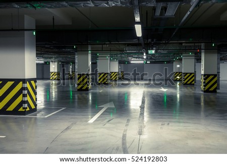 Parking garage, underground interior with a few parked cars.