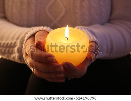 Burning candle in the hands of a girl.
Christmas candles