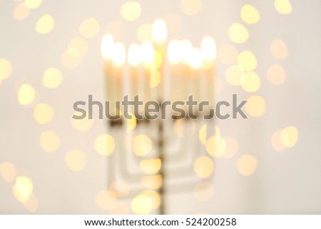 Blurred view of menorah with candles for Hanukkah on light background