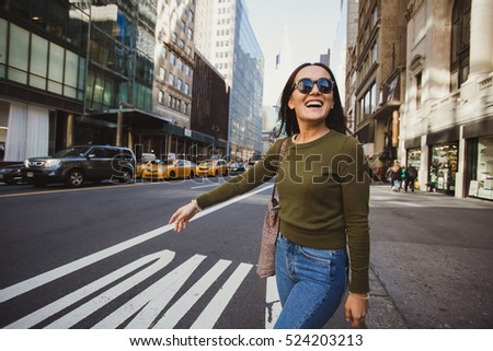 Pretty mixed race woman calling yellow taxi cab in Manhattan, New York. Inspiring photo of stylish student girl in the big city.