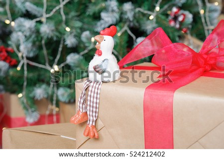 the symbol of the new 2017 rooster on the background of Christmas tree and boxes with gifts