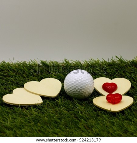 Wooden hearts shape with golf ball on green grass , idea love and Valentine's for golfer.