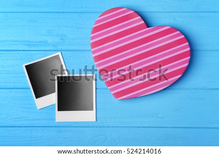 Heart shaped gift box and photos on blue wooden background