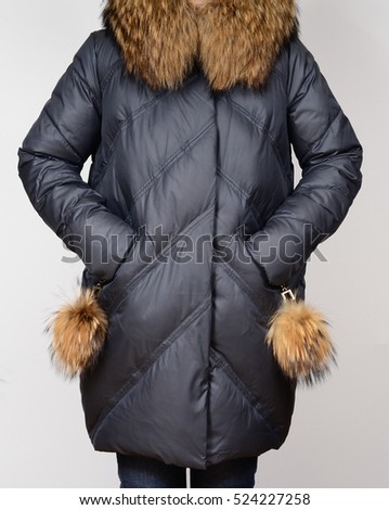 Winter down jacket with red fox collar isolated on grey background. Down jacket on model without face. Outerwear. Dark grey down jacket. Cloth. Grey coat. Nobody.