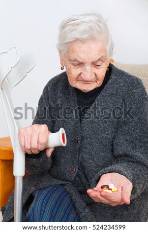Picture of a senior woman sitting in her apartment and holding pills