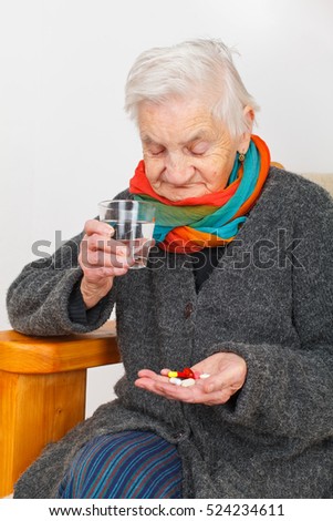Picture of a senior woman sitting in her apartment and holding pills