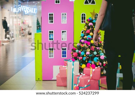 girl looks in black on colorful acid decorations on Christmas tree presents underneath. knitted woolen balls of pink and green color decorated with an artificial tree in nursery. 