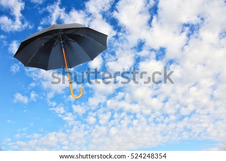 Wind of change concept.Black umbrella flies in sky against of pure white clouds.Mary Poppins Umbrella. Royalty-Free Stock Photo #524248354
