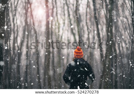 Woman with orange hat enjoys snow in the forest 