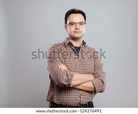 Casual young man in shirt standing over gray background