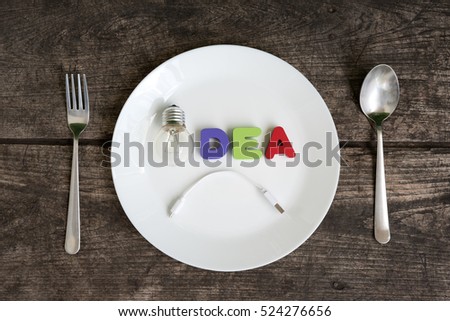Fail Concept, Big light bulb idea glowing with sadness on a plate with spoon and fork on grungy table