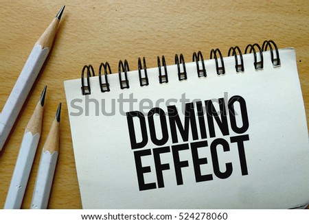 Domino Effect text written on a notebook with pencils