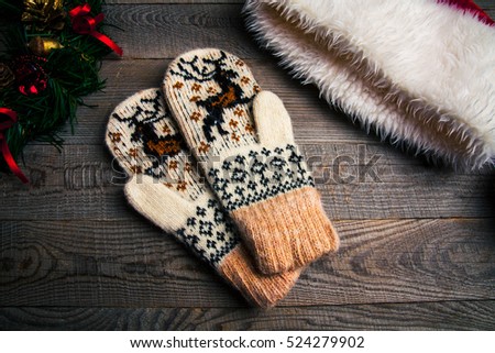 Christmas candle on vintage wooden background. Snowmen and beautiful ribbon. festive decorations. Classic knitted set of mittens and hats