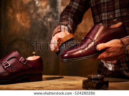 Man polishing leather shoes with brush. Royalty-Free Stock Photo #524280286