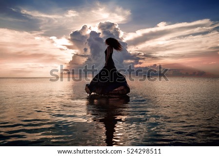 Elegant woman dancing on water. Sunset and silhouette. 