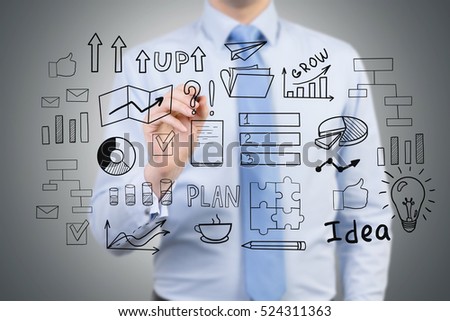 Close up of a businessman in a blue shirt who is drawing a startup idea sketch on a glassboard.