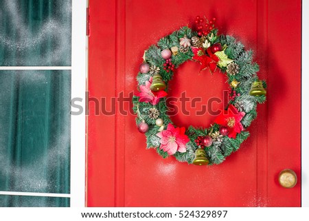Christmas wreath with baubles, cones and evergreen boughs on a red door. Texture and background 