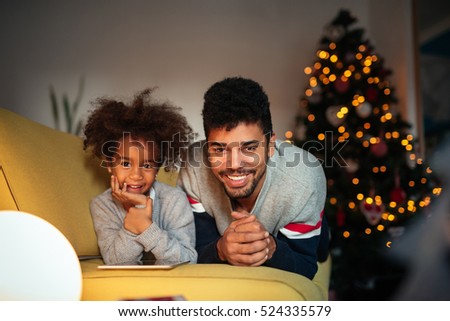 Dad and daughter using a tablet at home during winter holidays.